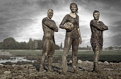 Rugby team posing for a group pic in the mud