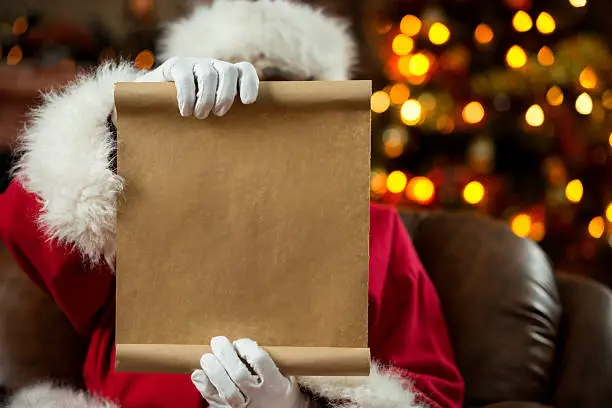 Photo of Santa Claus reading a wish list at home.