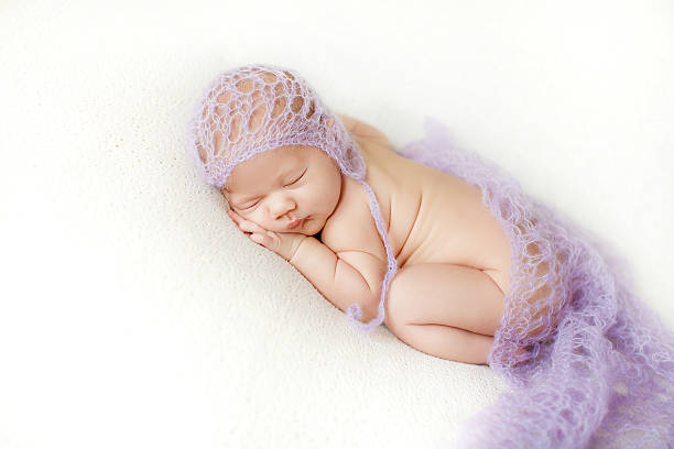 istock Newborn baby sleeps curled up in bed 489808402