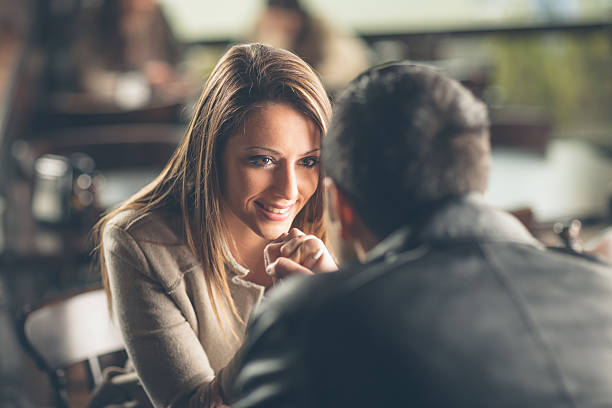 Romantic couple flirting at the bar Romantic young couple dating and flirting at the bar, staring at each other's eyes charming stock pictures, royalty-free photos & images