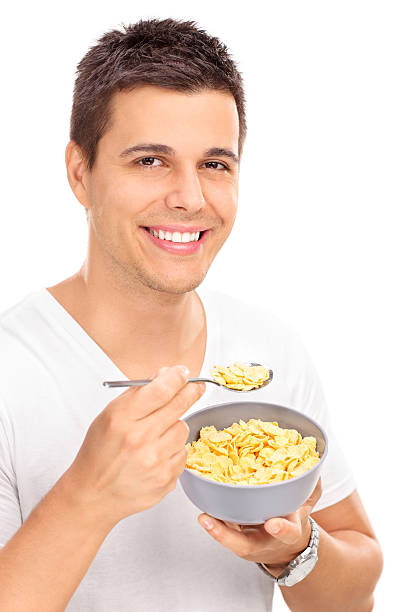 istock Cheerful young man eating cereal with a spoon 489809922
