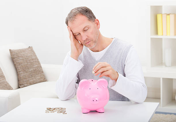istock Tired Man Inserting Coin In Piggybank 489816148