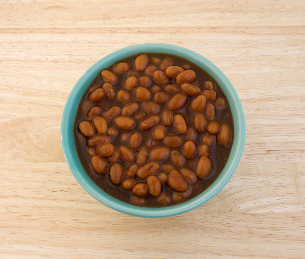 Country style baked beans in a bowl on table Top view of a bowl filled with country style baked beans on a wood table top. baked beans stock pictures, royalty-free photos & images