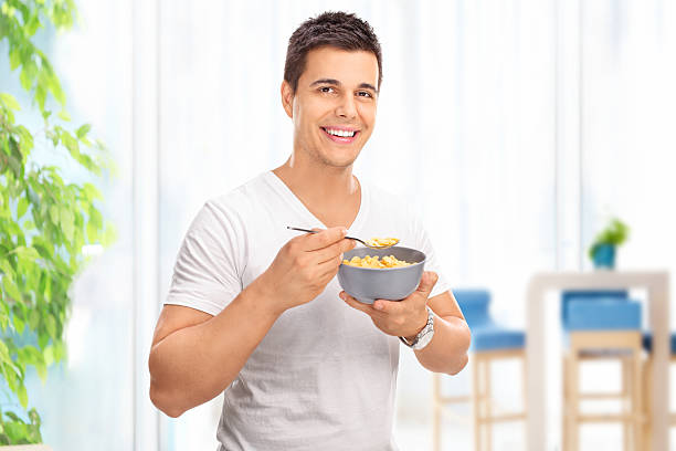 istock Young cheerful man eating cereal from a bowl 489830860