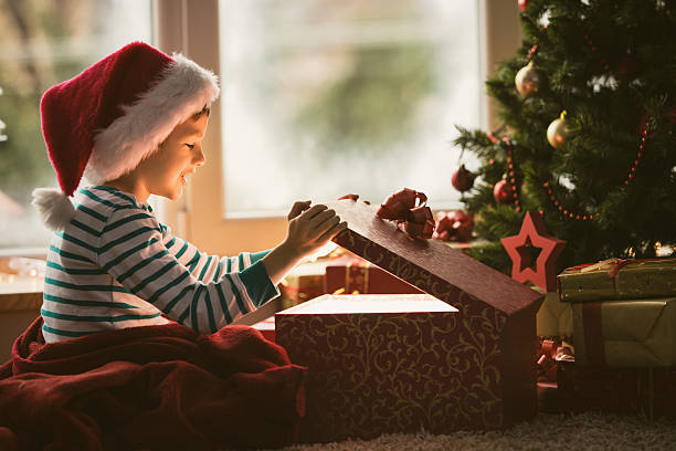 menino abertura presente de natal - christmas tree christmas gift christmas present - fotografias e filmes do acervo
