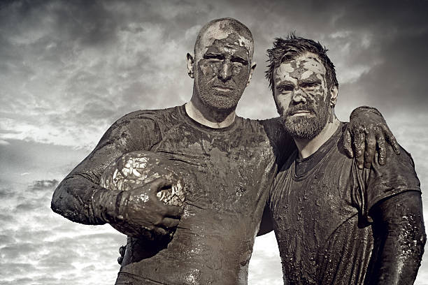 istock Two men posing with rugby ball in mud 489834510