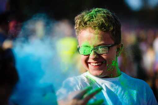 Teenager boy having fun, covered with color powder during the Festival of Colors