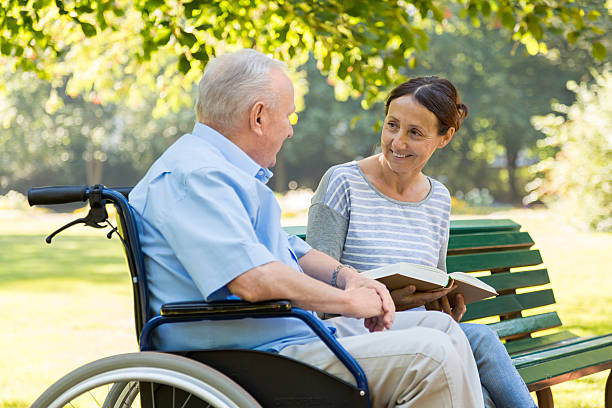 istock Caregiver and senior man sitting on park bench 489836694