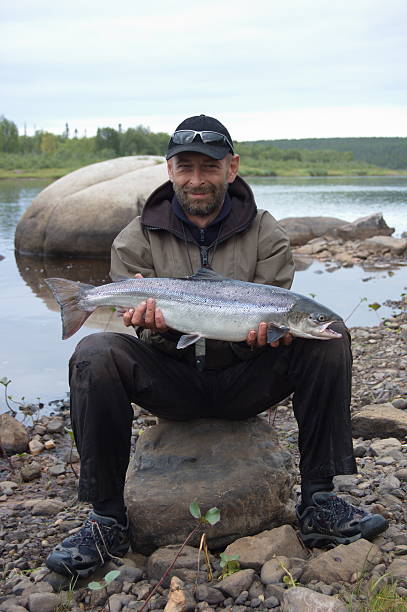 рыбак обладает большим лосося на берегу реки северной. - catch of fish water river salmon стоковые фото и изображения