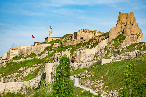 Van, Turkey - May 23, 2015: Tourists walking at castle road and castle and Turkish flag is flying near the minaret in Van Castle of Turkey at sunny day condition. 