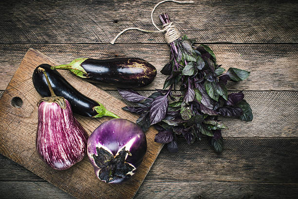 istock Aubergines and basil on chopping board and wooden table 489841674