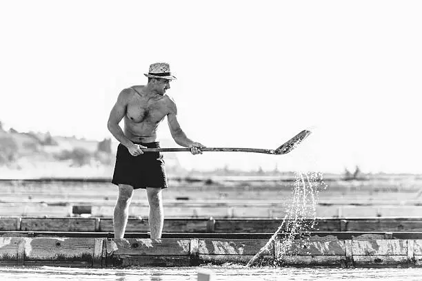 Man working with showel at salt pans. Black and white image.