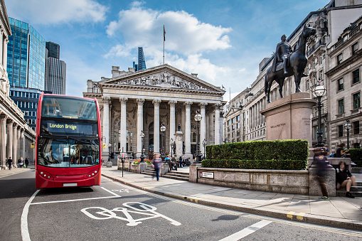 Bus waiting in front of the London Stock Exchange on a sunny day.