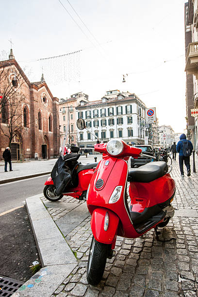 Milan, Italy - December 22, 2014: Red Vespa parked on Milan street. People walking on the street. 