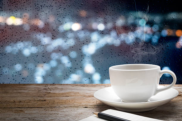 istock hot coffee cup on wooden table and drops of rain 489871042
