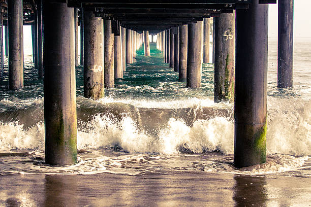 Waves Crashing Between The Columns Underneath The Santa Monica Pier stock photo