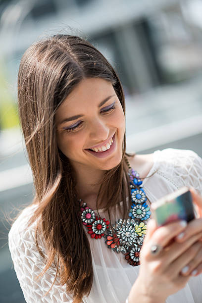 istock Young beautiful woman with white dress using mobile smartphone 489877924