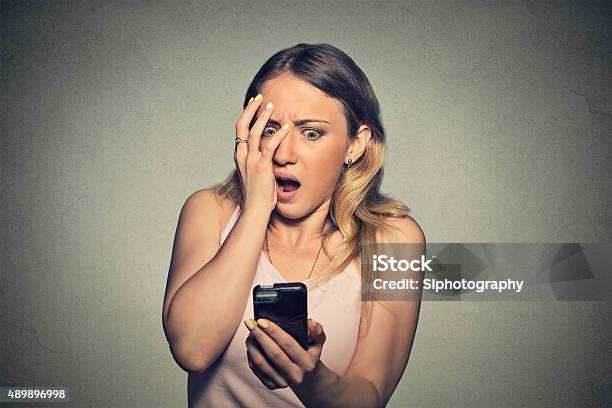 Anxious Scared Girl Looking At Phone Seeing Bad News Stock Photo - Download Image Now