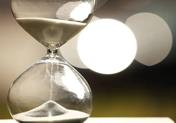 Modern Hourglass -- sand trickling through the bulbs of a crystal sand glass. every second counts. symbol of time. countdown. 