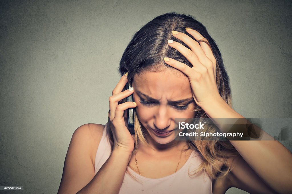 young woman talking on mobile phone looking down Portrait unhappy young woman talking on mobile phone looking down. Human face expression, emotion, bad news reaction. Using Phone Stock Photo