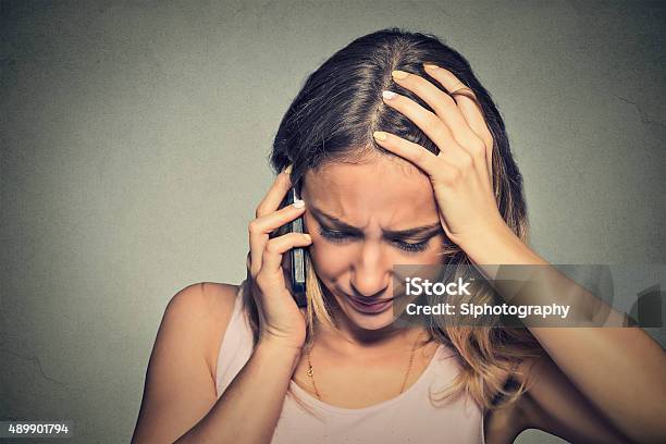 Young Woman Talking On Mobile Phone Looking Down Stock Photo - Download Image Now - Using Phone, Sadness, Despair