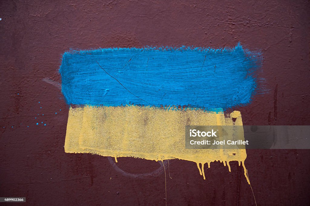 Ukrainian flag painted on metal wall The blue and yellow colors of the Ukrianian flag roughly painted on the metal wall of a pedestrian overpass in Mariupol, Ukraine. Mariupol Stock Photo