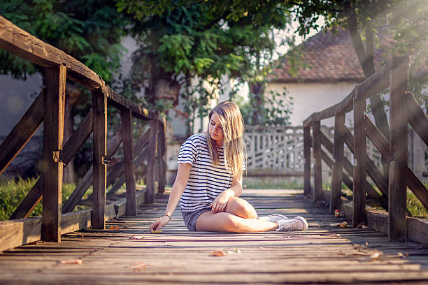 young woman sitting on the bridge , a very pretty girl enjoing sun 
