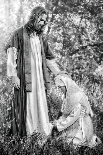 A Hebrew woman kneeling at Christ's feet touching the hem of his robe.  She had great faith in his ability to heal her from her sickness.