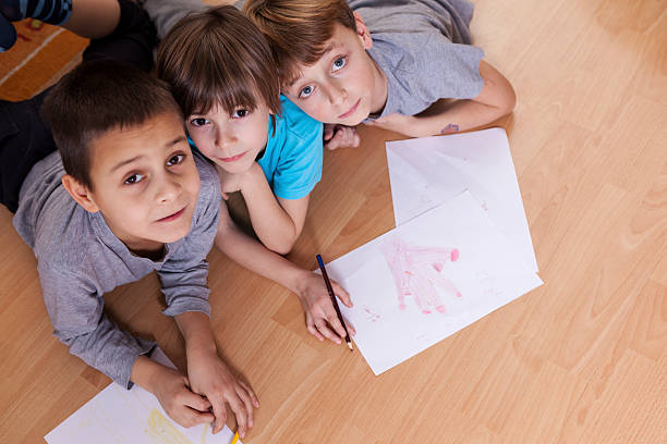 istock Children looking at the camera and drawing on the floor 489904142