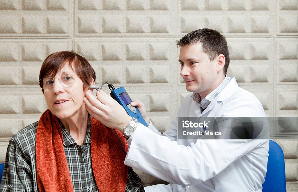 Ear exam on an old lady Doctor perfoming a hearing test to a senior woman in a soundproog office.  Senior Adult Stock Photo