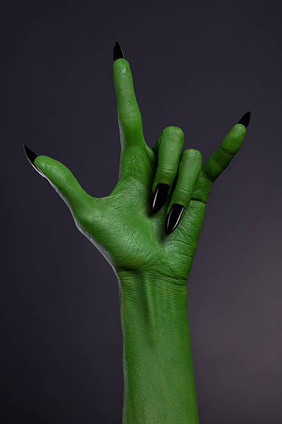 Green hand with black nails showing heavy metal gesture stock photo