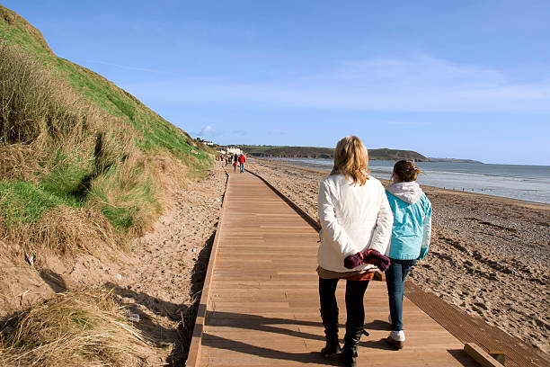 mother and daughter on beach boardwalk stock photo