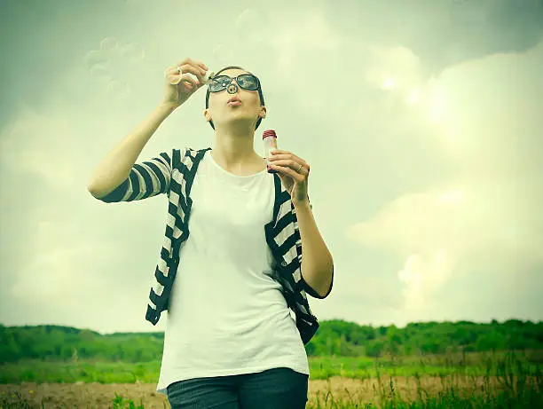Young girl blowing soap bubbles in park