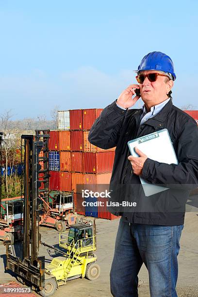 Manual Worker Phoning In Front Of Containers Stock Photo - Download Image Now - 40-49 Years, 50-59 Years, Adult