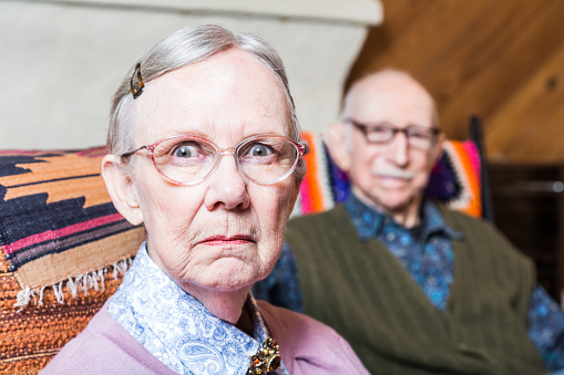 Old couple seating in livingroom woman scowling