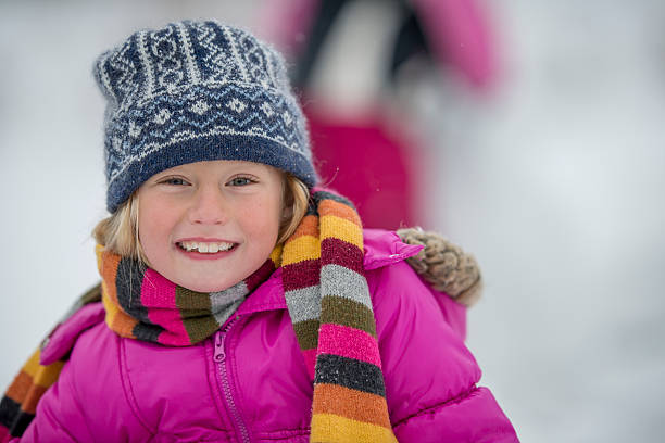 Royalty free stock photo of 6 years old girl smiling. She is lying in the snow.