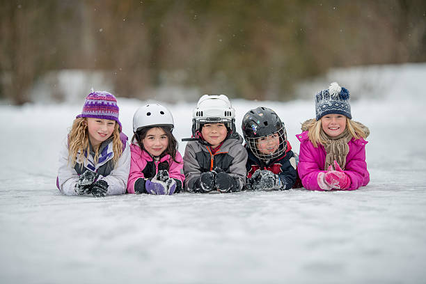 dzieci leżące w wierszu na lodzie - ice skating ice hockey child family zdjęcia i obrazy z banku zdjęć