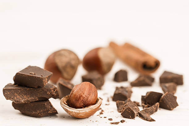 istock Broken chocolate bar, hazelnut and cinnamon on wooden background, close-up 489933706