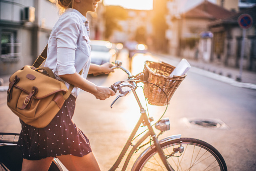 Young woman doing her business chores on the bicycle around the city; bicycle is being in the firs plan on the photo; basket is stuffed with documents and digital tablet 