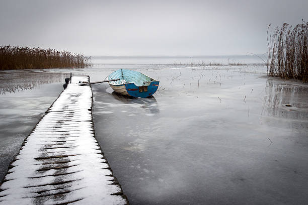 istock Old boat in a frozen lake winter 489937314