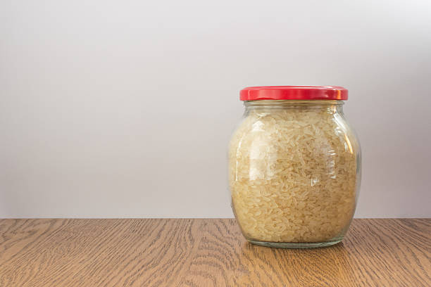 istock Full glass jar with rice closed red cap on wooden 489948376