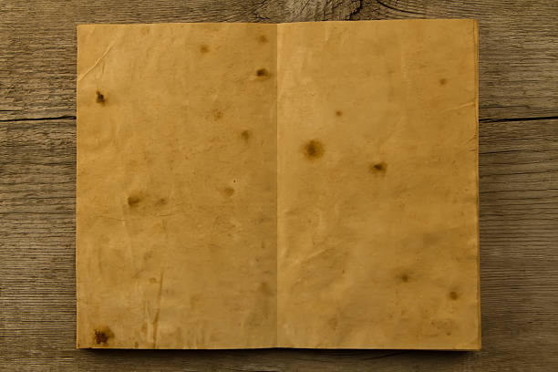 istock open old vintage book on the aged wooden background. 489951176