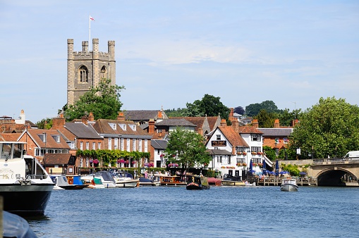 Henley-on-Thames, United Kingdom - July 10, 2015: View along the River Thames towards the Parish Church of St Mary the Virgin with people enjoying the sunshine, Henley-on-Thames, Oxfordshire, England, UK, Western Europe.