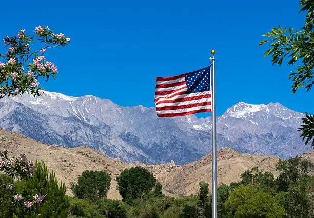 An American flag with Sierra Nevada mountain range in California in the background.