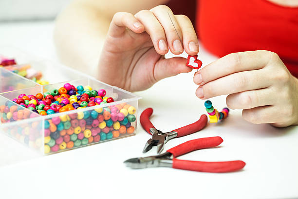 Woman making necklase from colorful plastic beads stock photo