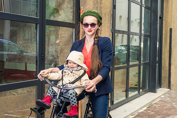 Trendy mother and daughter riding a bicycle in the city