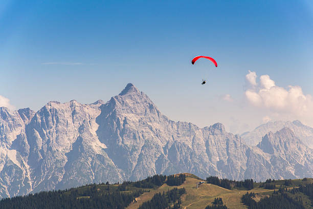 Paraglider flyes over mountains near Saalbach-Hinterglemm  in Alps, Austria