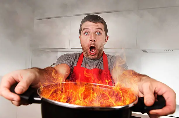 Photo of inexperienced home cook holding pot burning fire in panic stress