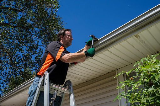 Worker repairing a gutter on a customers home.