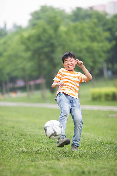 istock boy playing football at park 490024222